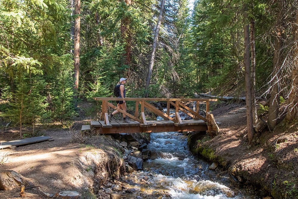 hiker crossing bridge of Sawmill Trail in Breckenridge, CO