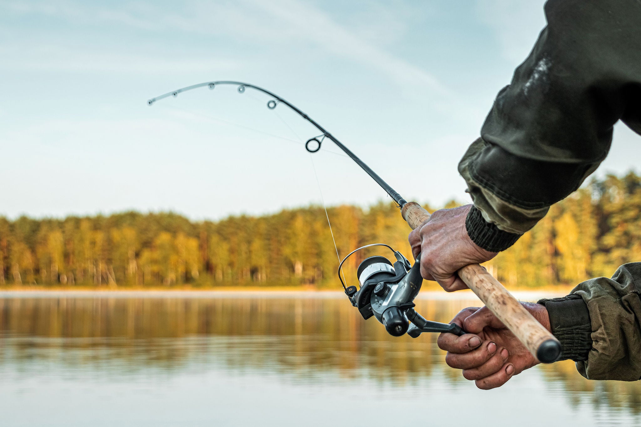 Angler casting his reel over the open lake waters.