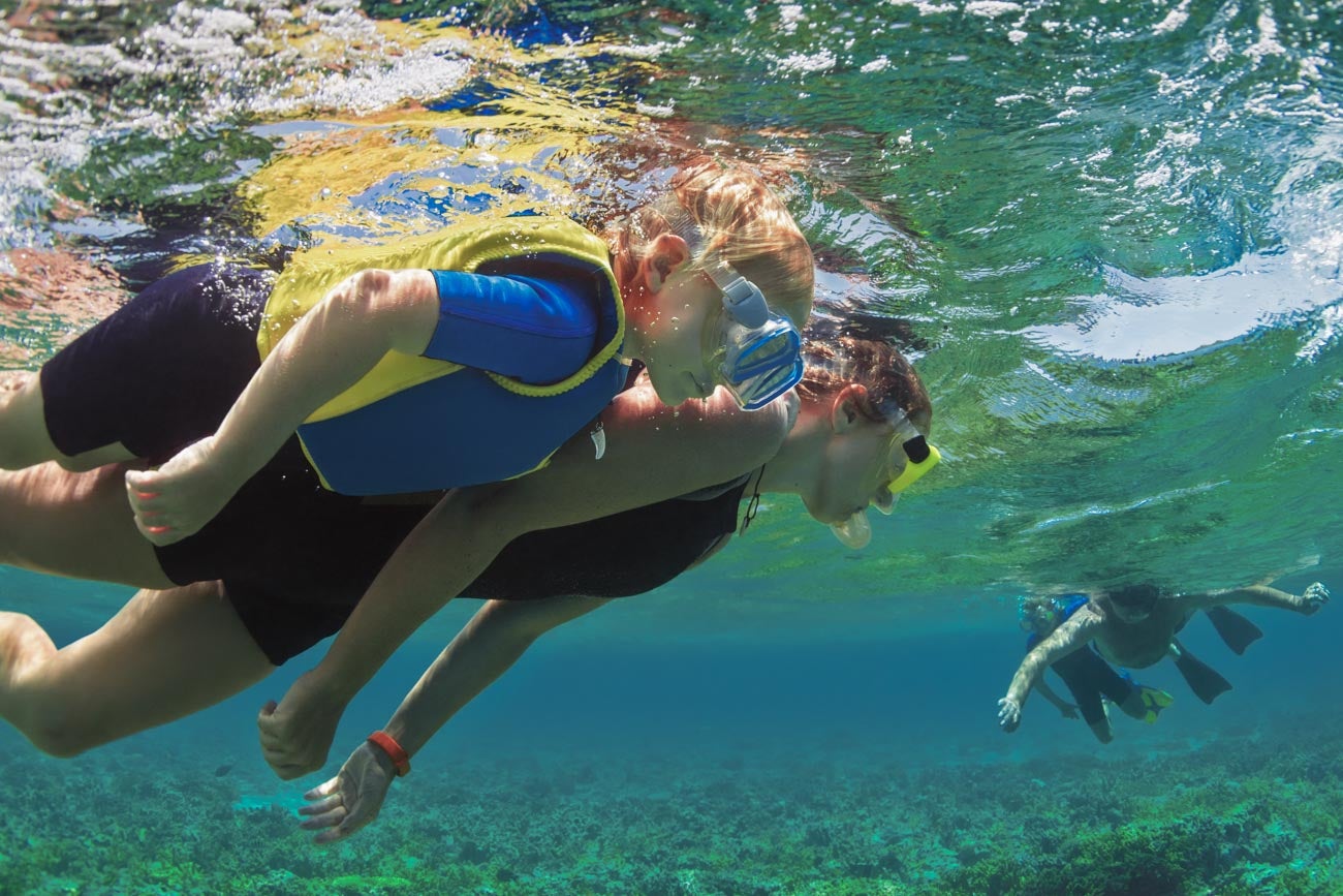 1070602734 Happy family - father, mother, kids in snorkeling mask dive underwater with tropical fishes in coral reef sea pool. Travel lifestyle, watersport adventure, swimming on summer beach holiday with child.