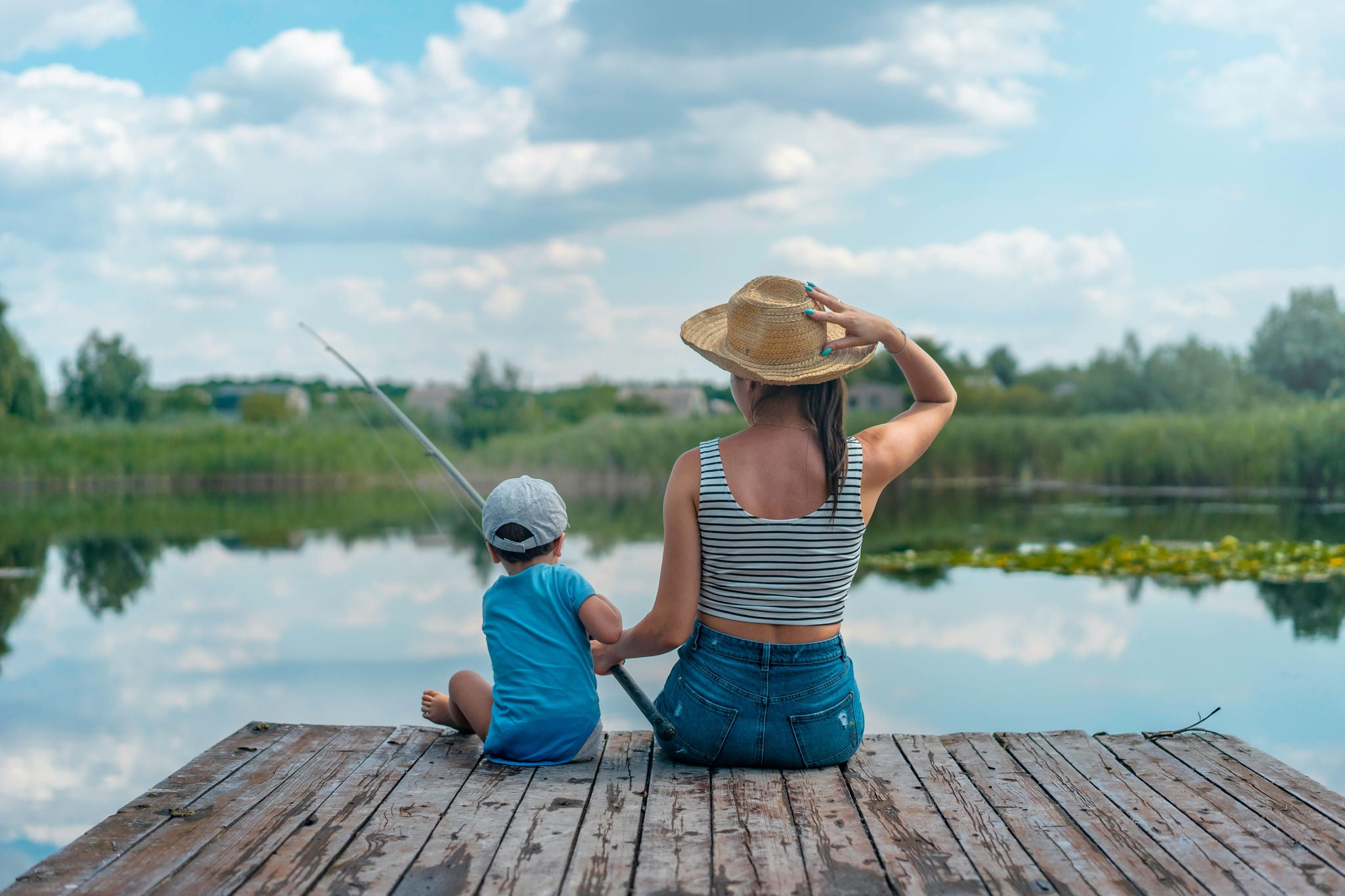 Mother and child fishing off a dock together.