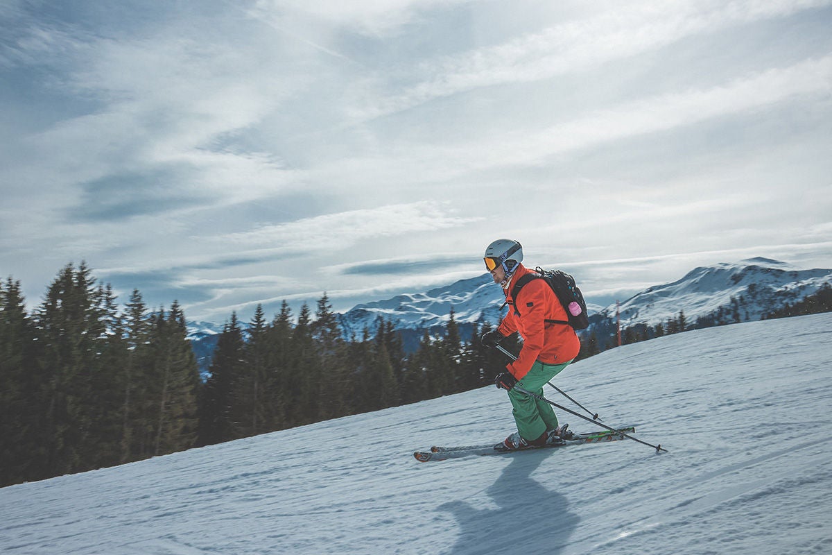 Person in orange coat skiing down mountain.