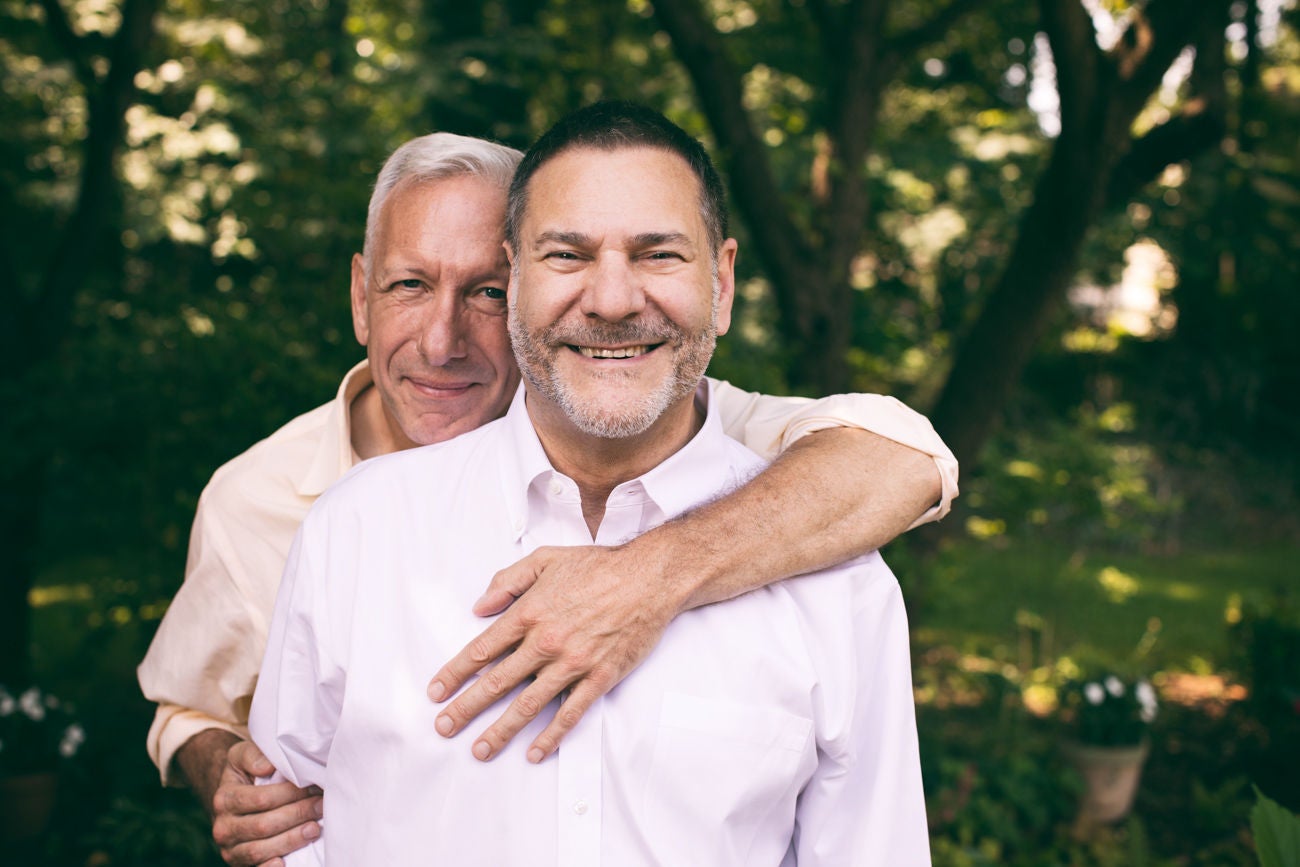 973370780 portrait of a loving middle-aged gay couple surrounded by nature.