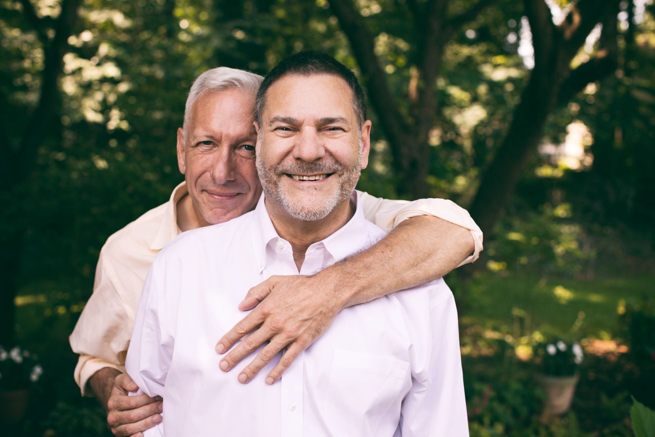 portrait of a loving middle-aged gay couple surrounded by nature.