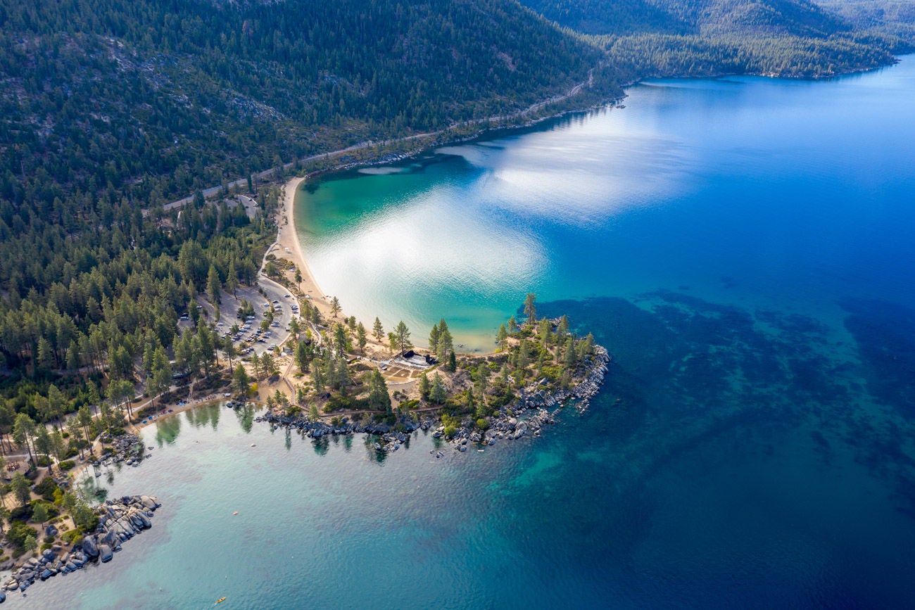 1043403752 Aerial View of Lake Tahoe Shoreline with Mountains and Turquoise Blue Waters