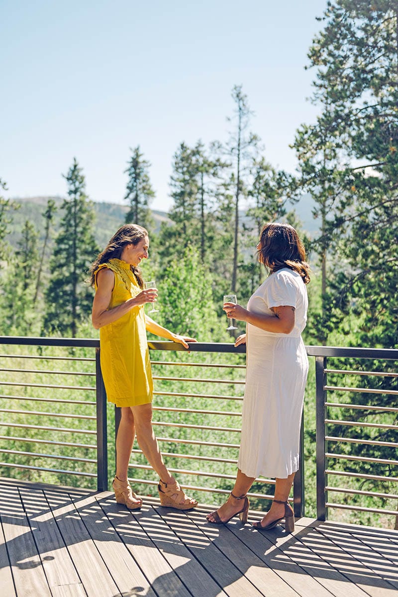 two women conversing on the balcony of a mountain home