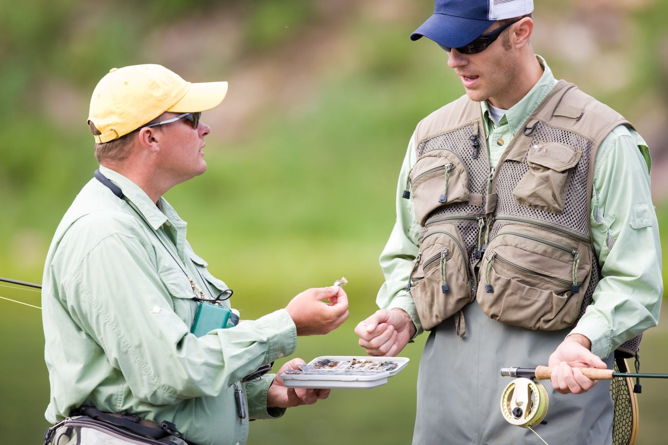 GET INTO FLY FISHING IS BY HIRING AN EXPERIENCED GUIDE. Two Fly Fisherman Discussing Lures